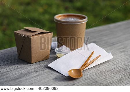 Craft Packaging Of Asian Food With Spoons And Napkins On A Wooden Bench.