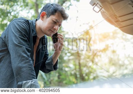 Man Using Phone For Contact Maintenance Car Service. Man Trying To Repair A Car Engine, Looking Insi