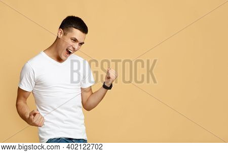 Happiness, Expression Of Success, Victory And Good Luck In Business. Excited Teen Guy In White T-shi