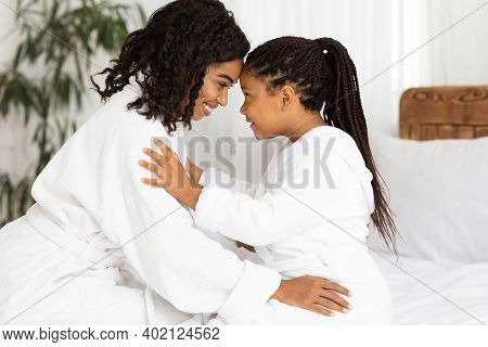 Bonding With Mom. Little Black Girl And Mother Wearing Bathrobes Hugging And Touching Foreheads, Enj