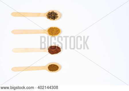 Various Seeds In Wooden Spoons On A White Background. Seeds Of Beet, Mustard, Lettuce, Arugula, On A