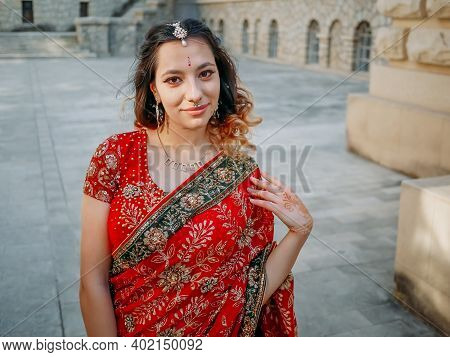 Young Beautiful Indian Woman Walks On Ancient Architecture Streets Of City Of India Dressed In Red S