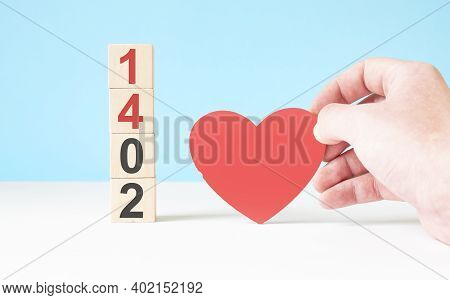 The Word 14 February With A Red Wood Heart. Wooden Cubes Against Red Background. Love, Romance, Rela