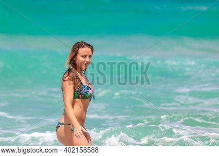 Young Beautiful Girl Enjoys The Sea And The Waves, Laughing Raising Her Hands Up In A Black Fashiona