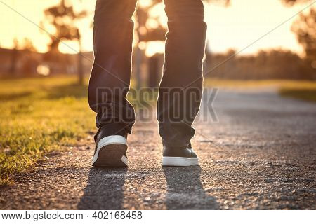 Close Up Of Walking Man At Sunset In The Park. Walking Outdoors. Closeup On Shoe, Taking A Step