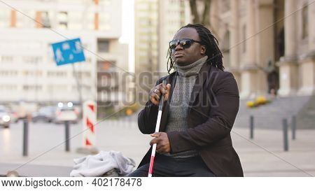 Blind Black Man Sitting On The Bench And Holding Walking Long Cane. High Quality Photo