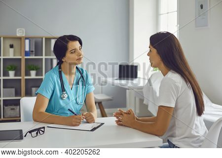 Young Doctor Therapist Listening To Woman Patient In Medical Clinic