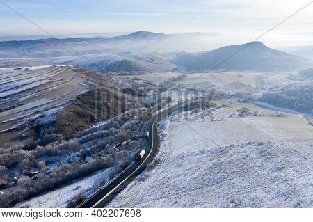 Aerial View Of A Winding Road With Trucks In A Frozy Winter Sunny Day
