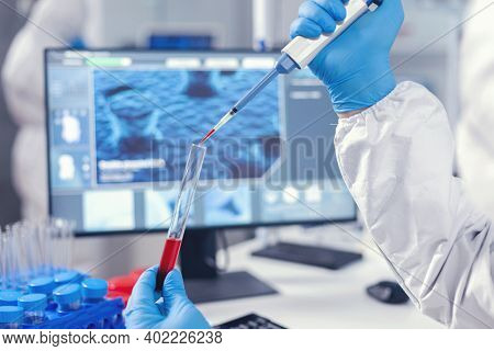 Medical Researcher Dripping Blood Into A Test Tube From A Micropipette. Doctor Working With Various 