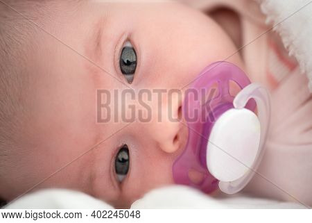 Close Up Of Newborn Baby Lying On Its Side With White Soother In Mouth. Newborn Theme