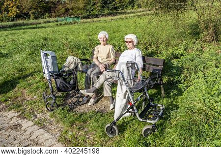 Schwalbach, Germany - October 19, 2014: Elderly Female Couple Enjoys The Spring Sun While Sitting On