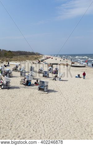 Zempin, Germany - April 20, 2014: People Enjoy The Sun At The Beach In The Roof Wickerd Chairs In Us