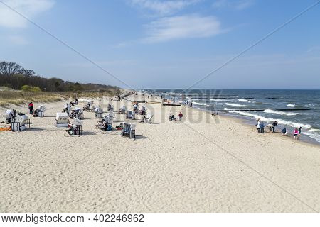 Zempin, Germany - April 20, 2014: People Enjoy The Sun At The Beach In The Roof Wickerd Chairs In Us
