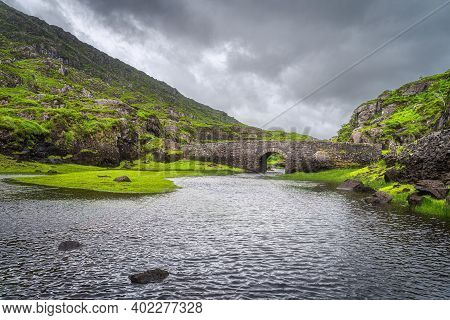 Small Stone Wishing Bridge Over Winding Stream In Green Valley, Gap Of Dunloe In Black Valley, Ring 