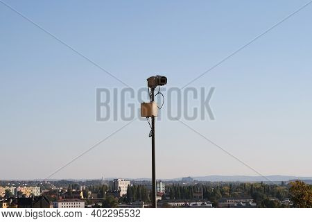 An Industrial Camera On A Mast That Is Aimed At The City.