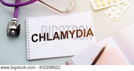 Stethoscope, Pills And Notebook With Chlamydia Word On Medical Desk.