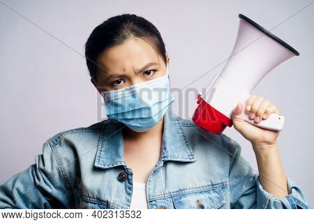 Asian Woman Wearing Protective Face Mask Shouting With Megaphone Isolated Over White Background.