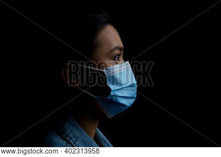 Asian Woman Wearing Protective Mask Isolated Over Background. Low Key.