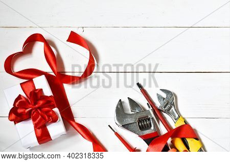 Wrenches, Screwdriver And Red Ribbon, Gift Box On A Wooden Background. Holiday Concept. Happy Father