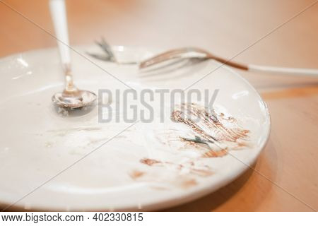 Finished Empty Dessert Plate With Spoon On Wood Table
