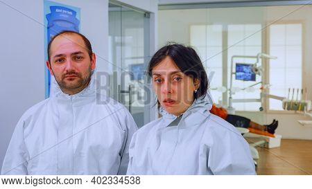 Portrait Of Team Doctor In Dental Office Taking Off Protective Masks Looking On Camera Having Marks 