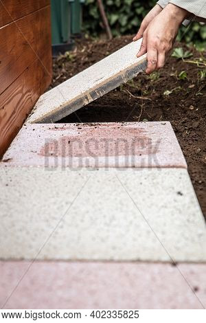 Man Is Laying Quadratic Tiles In The Garden, Building A Brick Path