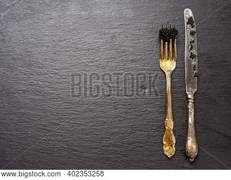 Fresh Grainy Black Paddlefish Caviar In Metal Fork On A Black Background, Top View, Copy Space