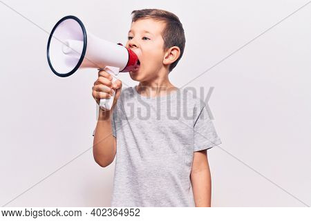 Adorable caucasian kid boy with angry expression. Screaming loud using megaphone standing over isolated white background