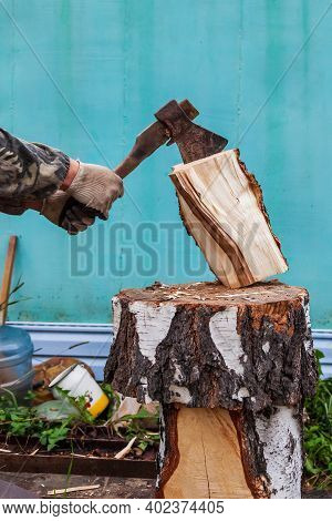 A Log Split In Half With An Ax On A Deck With Male Hands In Cloth Gloves And A Camouflage Jacket In 