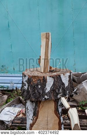A Log Split In Half With An Ax On A Deck With Male Hands In Cloth Gloves And A Camouflage Jacket In 