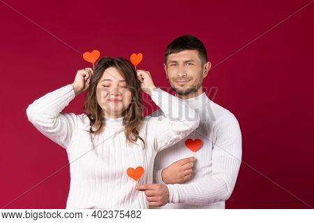 Young Couple Fooling Around And Having Fun On St.valentines Day. Red Background And Empty Space.