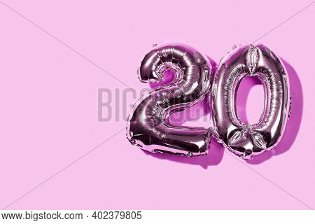 two number-shaped balloons forming the number 20, on a pink background with some blank space on the left