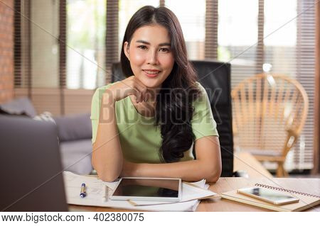 Happy Young Asian Businesswoman Looking Staight At Camera While Sitting And Working On Her Project U