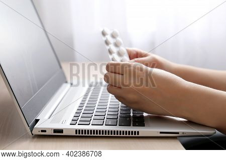 Female Hands With Pills On Laptop Keyboard. Woman Taking Medication During Work, Reading The Contrai