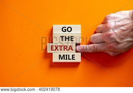 Go The Extra Mile Symbol. Wooden Blocks With Words 'go The Extra Mile'. Male Hand. Beautiful Orange 