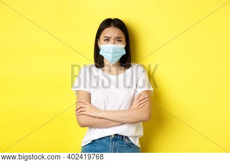 Covid, Health Care And Pandemic Concept. Asian Woman In White T-shirt And Medical Mask Cross Arms On