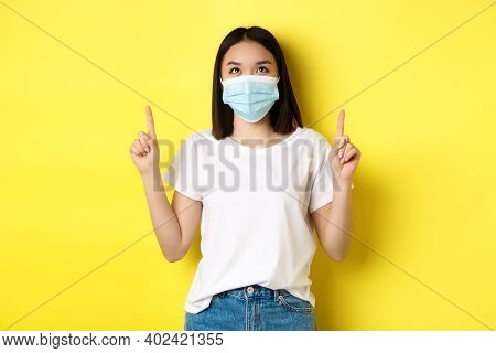 Covid-19, Pandemic And Social Distancing Concept. Young Asian Woman In White T-shirt And Medical Mas
