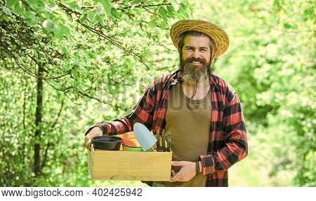 Bearded Farmer In Straw Hat With Wooden Box. Mature Man Gardener Working In Greenhouse. Brutal Male 