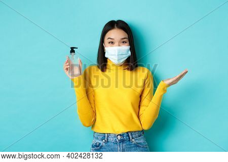 Covid-19, Social Distancing And Pandemic Concept. Cheerful Asian Woman Showing Hand Sanitizer, Recom