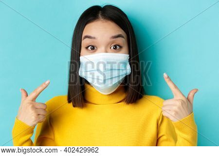 Covid-19, Social Distancing And Pandemic Concept. Close Up Of Surprised Asian Girl Pointing At Her M
