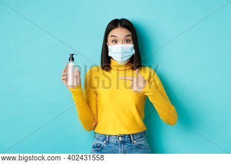 Covid-19, Social Distancing And Pandemic Concept. Enthusiastic Asian Woman In Face Mask Pointing Fin