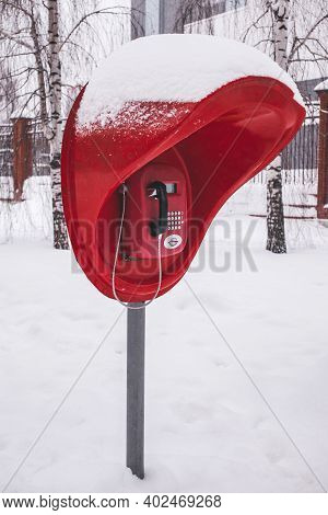 A Red Pay Phone In A Winter Park After A Heavy Snow Fall. Vertical Photo.