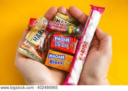 Tambov, Russian Federation - January 06, 2021 Woman Palms Full Of Haribo Candies. Yellow Background.