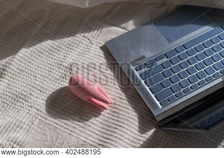 Clitoral Vibrator And Laptop On The Bed In A White Sheet