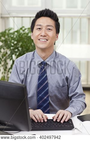 Businessman Using A Laptop And Phono In An Office High Quality Photo