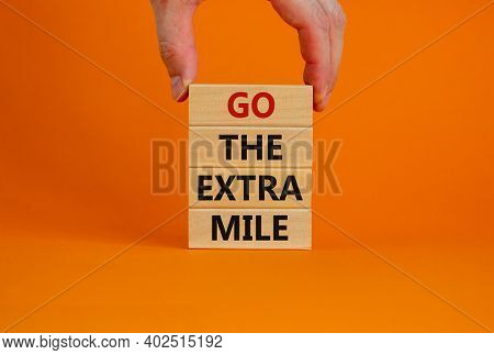 Go The Extra Mile Symbol. Wooden Blocks With Words 'go The Extra Mile'. Male Hand. Beautiful Orange 