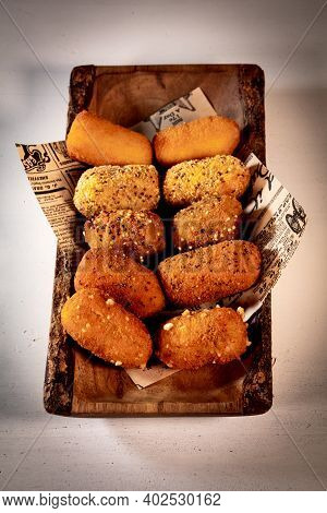 Aerial Shot A Traditional Spanish Food Of Croquettes, Presented On A Tray With Letter Paper.the Back