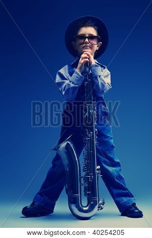 Retrato de um jazzman de menino pequeno bonito tocando seu saxofone. Estilo retrô.