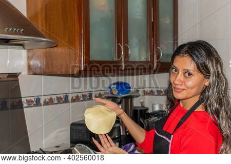 Young Woman Wearing A Red Shirt Preparing Some Tortillas With Her Hands On Her Kitchen House