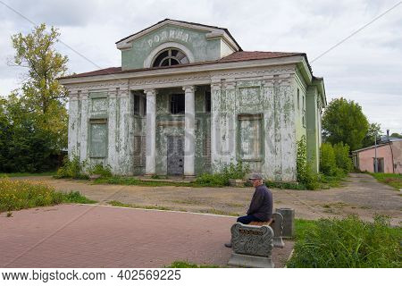 Kotelnich, Russia - September 15, 2018: Elderly Man Sits On A Bench Near The Closed Cinema 